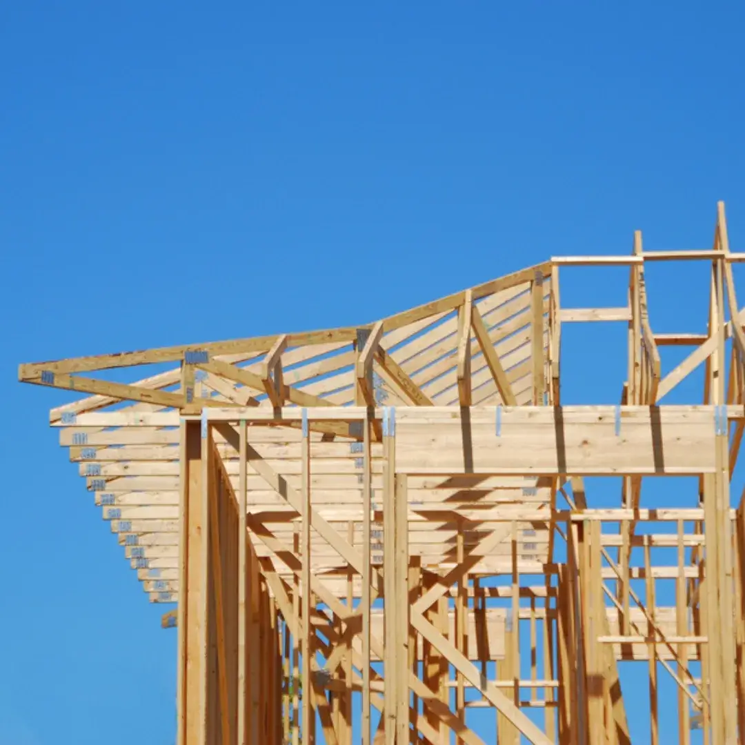 A modern house under construction with complex wooden truss design and framing structure.