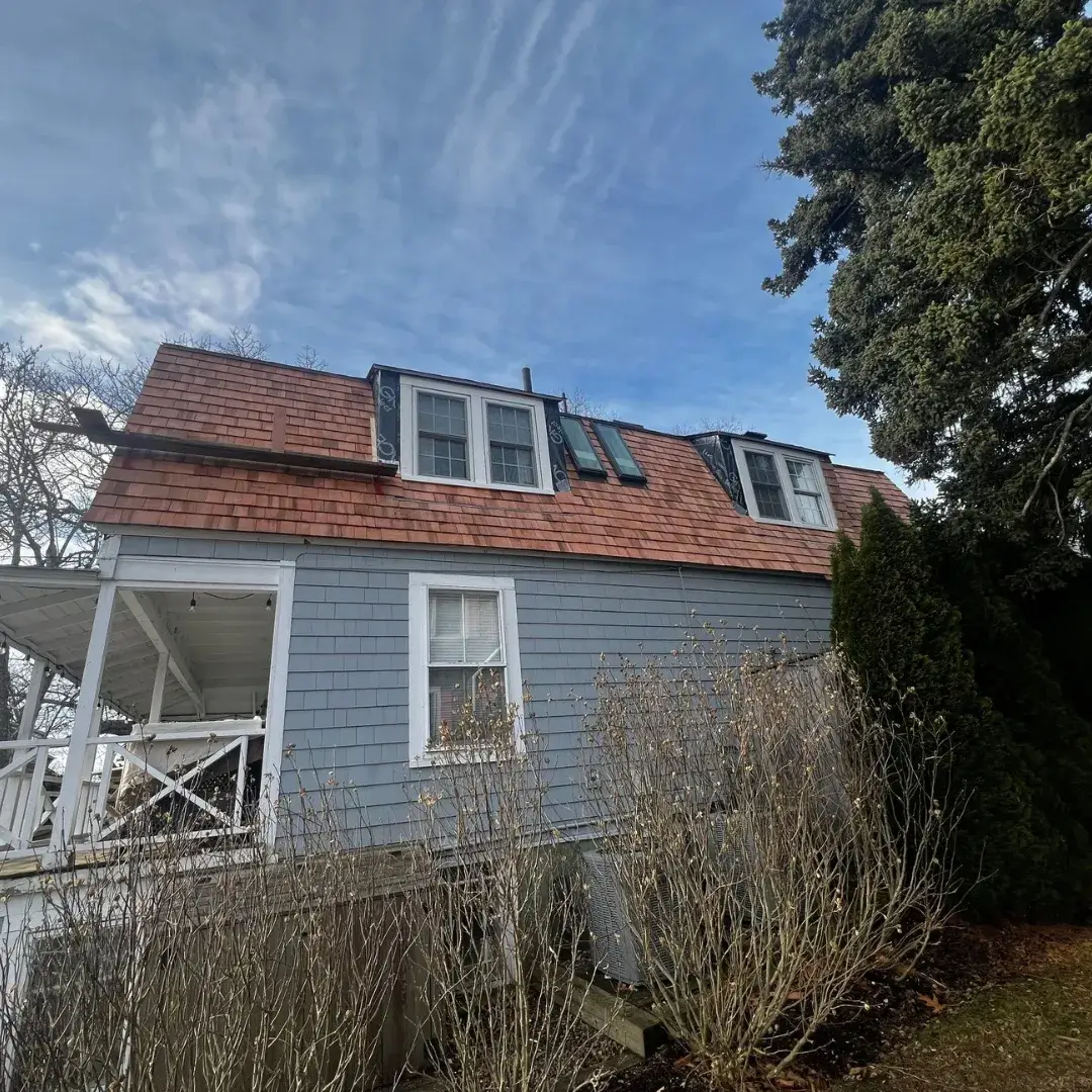 Side view of a house with a cedar shingle roof under construction.