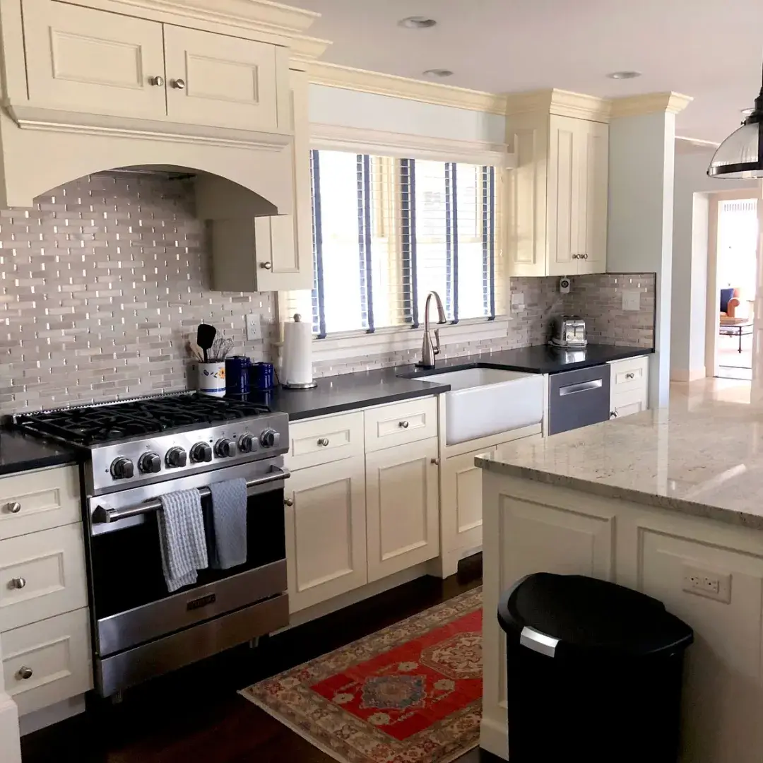 Traditional kitchen with cream-colored cabinets, black countertops and a farmhouse sink.