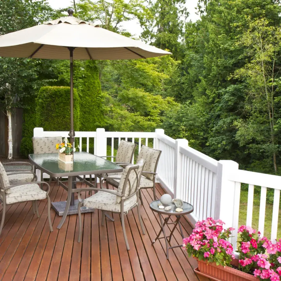 A charming backyard deck with a patio table, umbrella and vibrant flowers.
