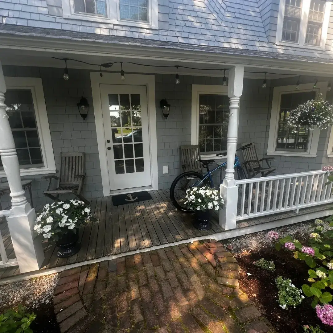 A charming front porch with flowers, rocking chairs and white railings.