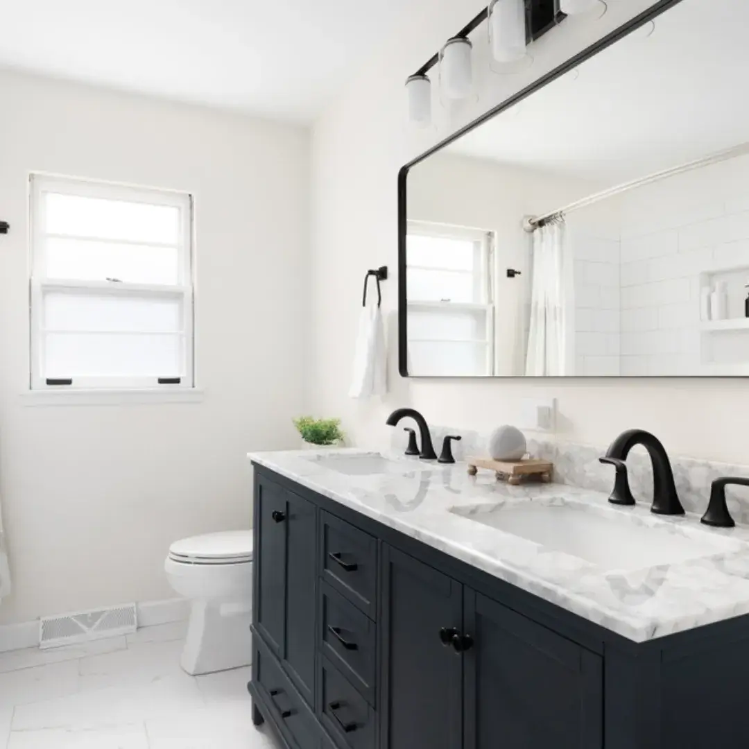 A modern bathroom with a black vanity, marble countertop and large mirror with black fixtures.