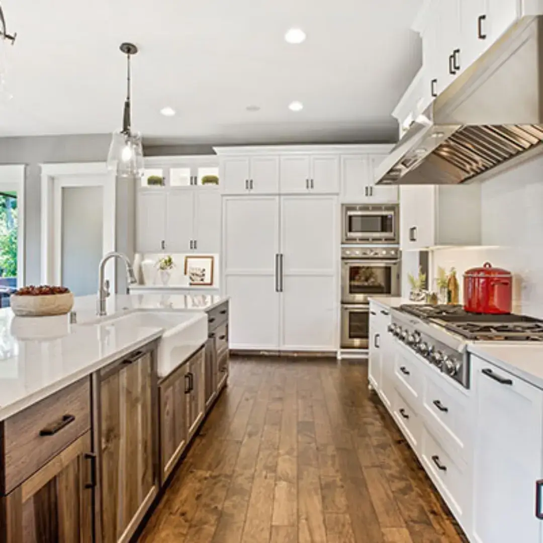 Modern farmhouse kitchen with a white and wood island, stainless steel appliances and bright lighting.