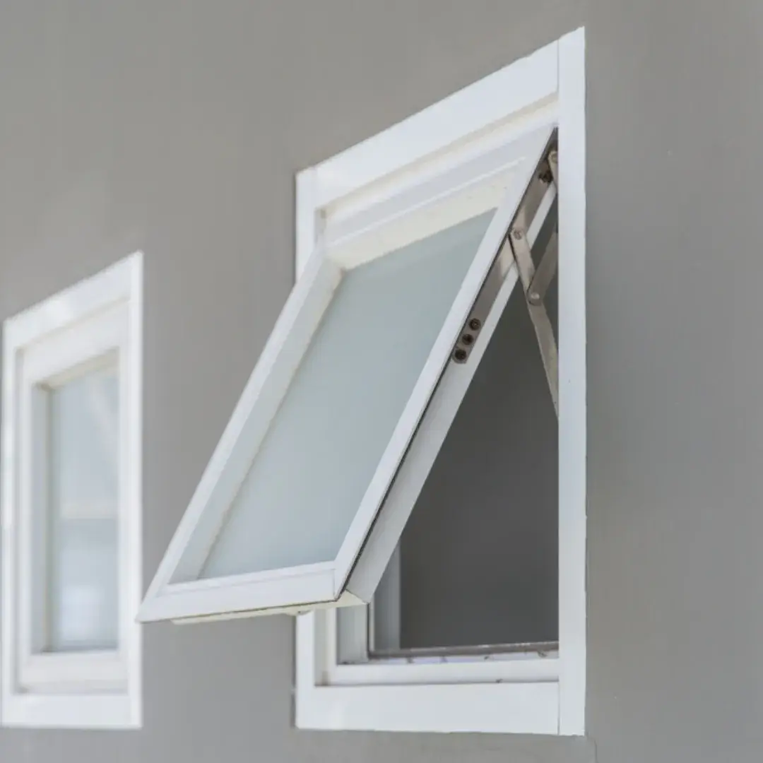 A white frosted awning window slightly open on a modern gray home exterior.