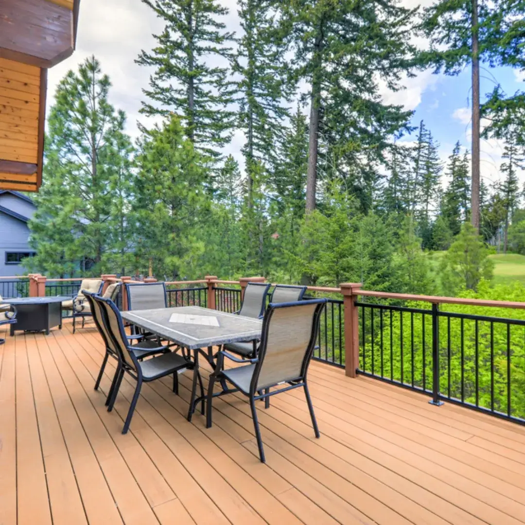 Spacious wooden deck with a dining table and a scenic view of the forest.